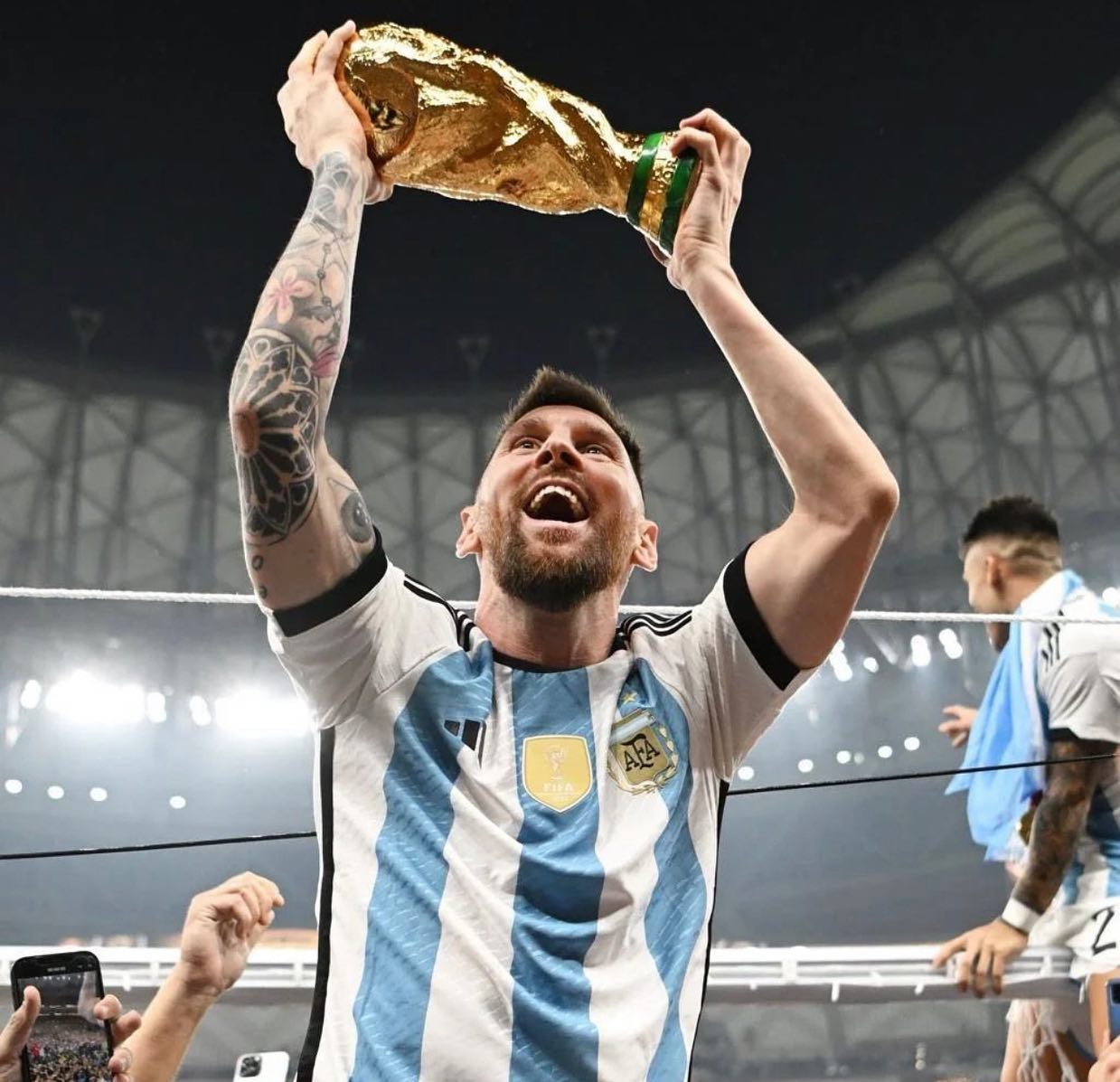 Lionel Messi lifting the World Cup trophy, smiling in his Argentina shirt