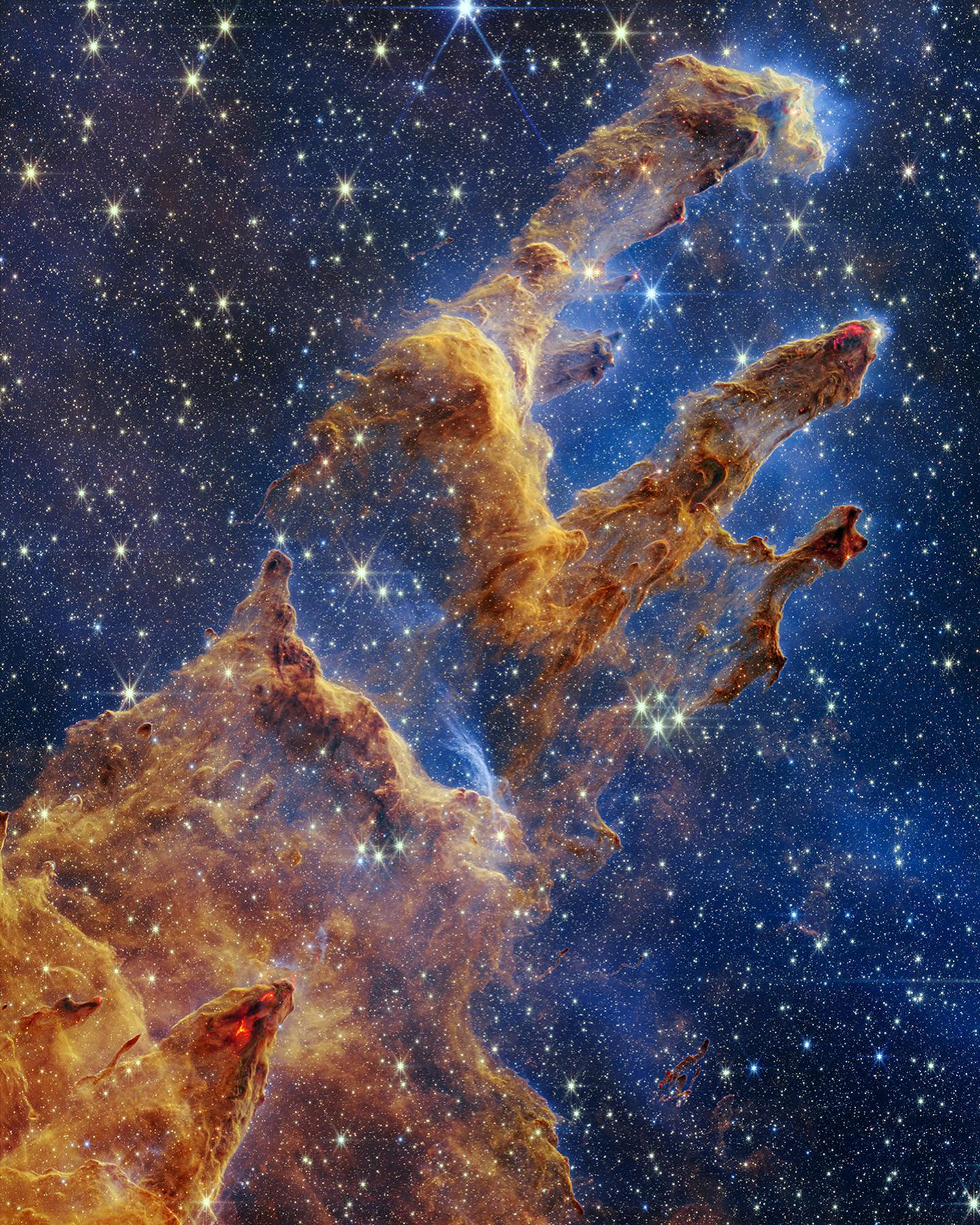 Glowing gold towers of interstellar dust against a deep blue field of stars